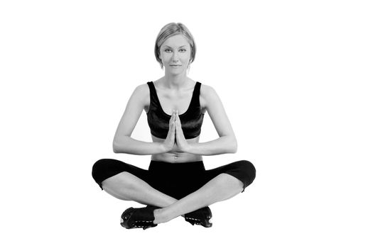 A blond young woman in a fitness outfit is sitting in a lotus position doing yoga. The picture is in B&W.