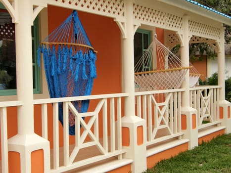 two hammocks suspended outside a bright orange house