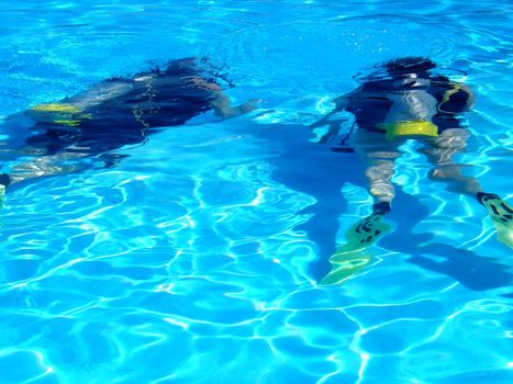 two people practising scuba diving in a swimming pool