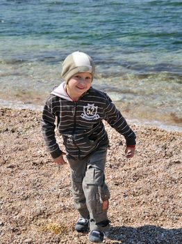 little boy is jumping on the beach in springtime he is smiling and happy