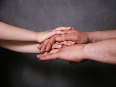 Hands of the father and his daughter on a grey background