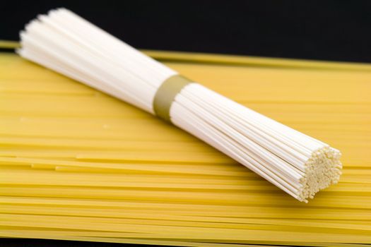 Spaghetti. White and yellow macaroni on a black background.