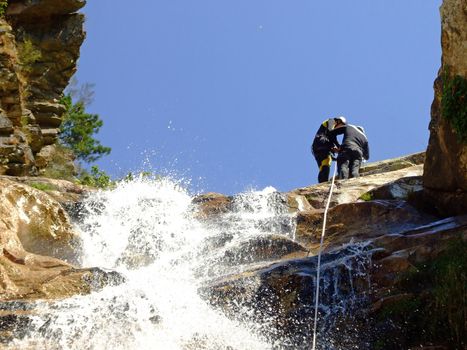 Couple prepering to descende a waterfall with roupes 