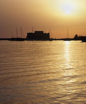 Medieval Castle of Paphos, Cyprus at sunset with the sea turning to liquid gold