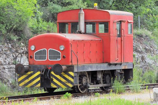 Red locomotive used to move wagons stopped on railroad