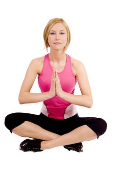 A blond young woman in a fitness outfit is sitting in a lotus position doing yoga