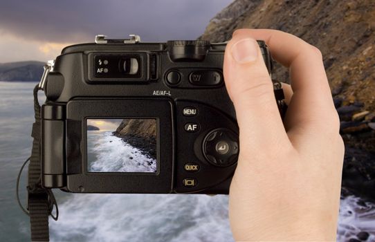 Digital Camera photo in a hand isolated on withe background. lcd screen and background can be easily edited