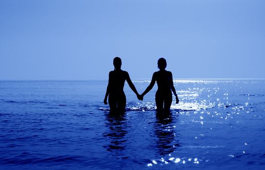 silhouette image of two bikini girls holding hands