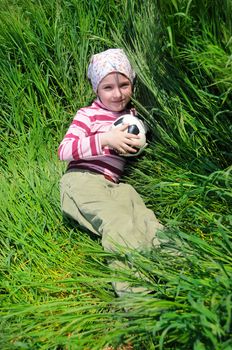 a girl plays with a ball in a grass