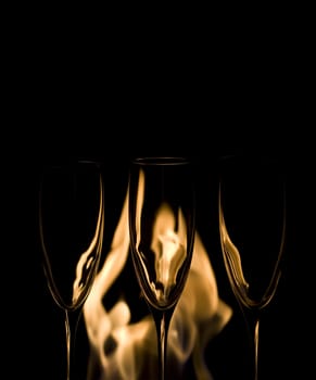 Three Crystal glasses and fire isolated on black  