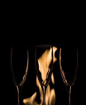 Three Crystal glasses and fire isolated on black  