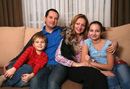 Mum, daddy, two children and yorkshire terrier on a sofa