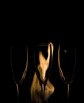 Three Crystal glasses and fire isolated on black  