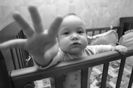 The small child in a bed. The face in a zone of sharpness, the hand is dim