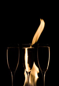 Three Crystal glasses and fire isolated on black  