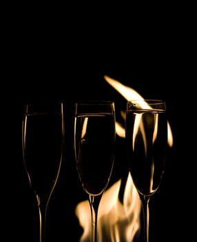 Three Crystal glasses and fire isolated on black  