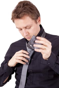 A young businessman is tying a tie