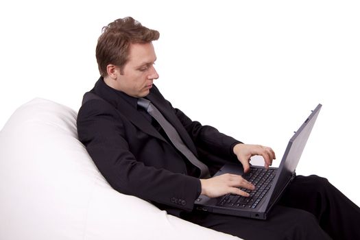 Business man is using a laptop while sitting in a fatboy sofa