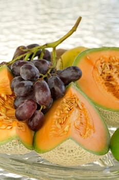 Grape and cantaloupe slices on a glass plate in natural light