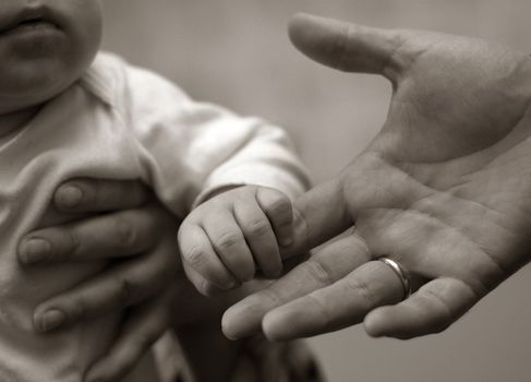The image of hands of parents and the kid. b/w+sepia