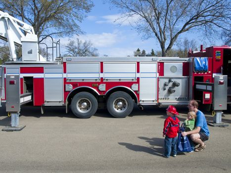 A father and two children observing a firetruck at a fundraiser for emergency services. Shot at Hawrelak Park in Edmonton, Alberta, Canada, May 9/09.