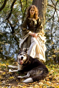 Lady in medieval dress and dog in the forest
