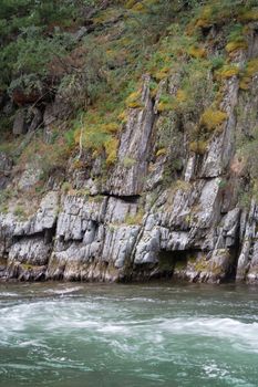 Green rock with trees and river
