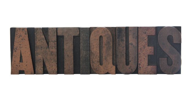 the word 'antiques' in old, ink-stained wood letters isolated on white