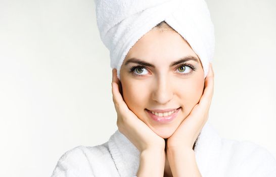 portrait of a pretty girl wrapped into the white towel and wearing a white dressing gown