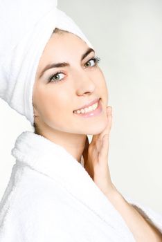 portrait of a pretty girl wrapped into the white towel applying cosmetics