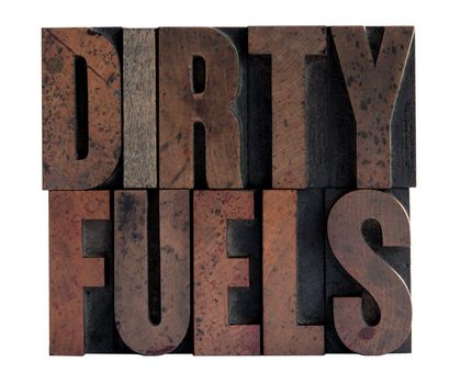 the phrase 'dirty fuels' in ink-stained wood type isolated on white
