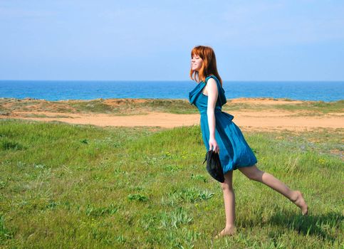 redheaded girl walking on the beach toward sun