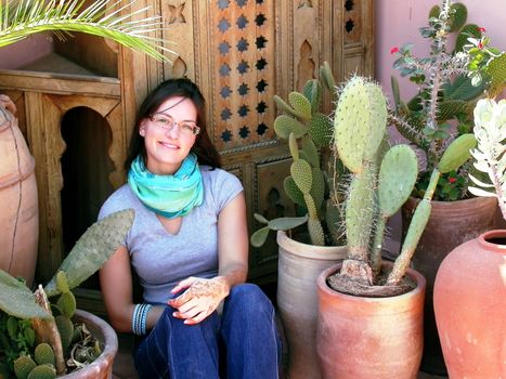 a woman is showing off her henna tattoo while sitting besides cactus plants