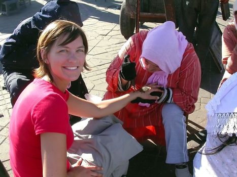 a tourist is having an artist paint a henna tattoo on her hand