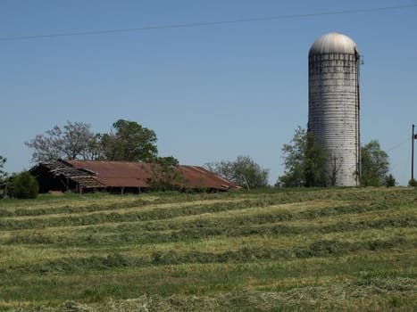 A tall farm silo in rural North Carolina with an old barn