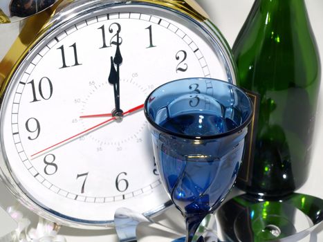 A clock reading 12:01 with a glass and a green bottle.