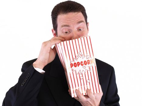 Adult male in a suit holding a popcorn bag and looking in. Isolated on a white background.