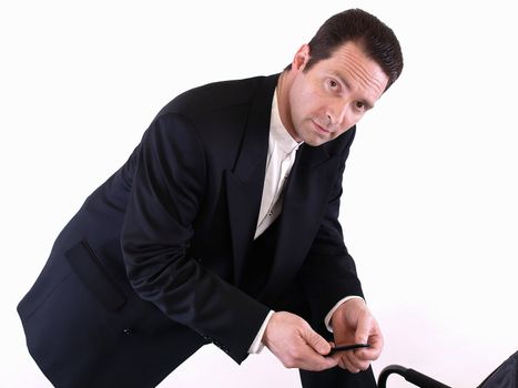 A standing man leans down on one knee to check an incoming text message on his cell phone.