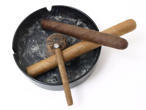 Three cigars resting in a dirty ashtray isolated on a white background.