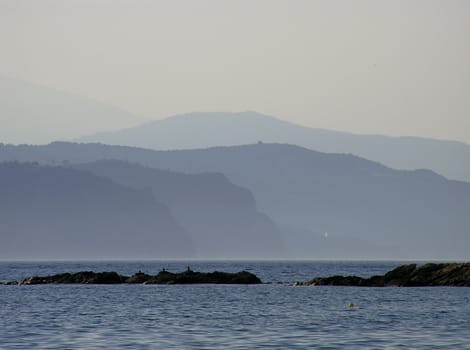 Landscape at sunset with reflection in sea water in blue colours fadeing in distance.