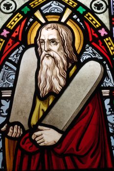 detail of victorian stained glass church window in Fringford depicting Moses with the tablets of covenant in his arms, interestingly without text, means he is pictured before climbing Mount Sinai