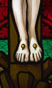 detail of victorian stained glass church window in Fringford depicting Jesus' feet nailed to the cross