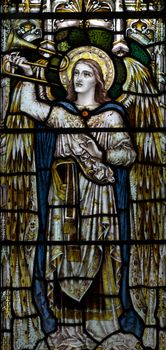 detail of victorian stained glass church window in Fringford depicting a typical victorian angel with a horn or trumpet in his hands