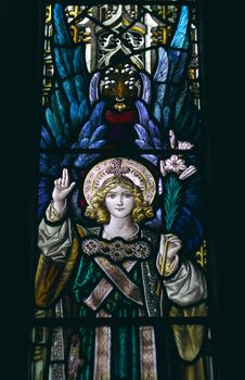 detail of victorian stained glass church window in Fringford depicting a typical victorian angel with a lily in his hands