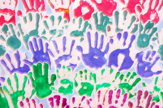 Many hand prints of children in different colors on white background