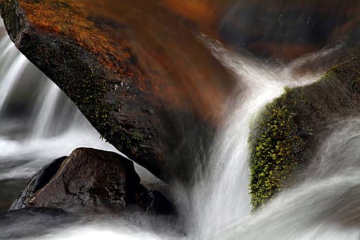Abstract background capture of water flowing between rocks.