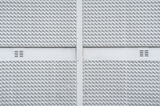 Ventilation holes in the 3d zigzag texture of a corporate building facade.