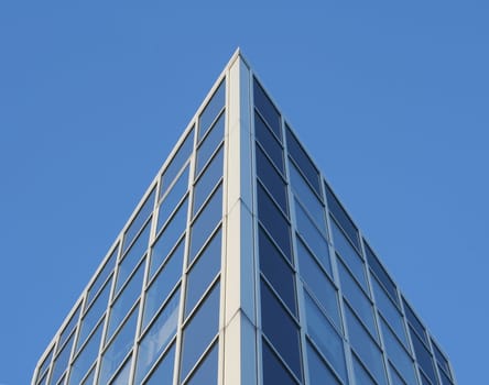 Corner of a modern office building against a clear blue sky. Glass facade.