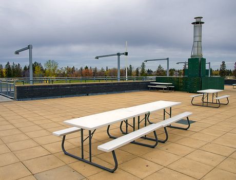 White picnic tables on a large outdoor deck.