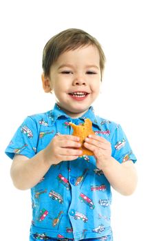 happy three year old boy eating a cookie and laughing